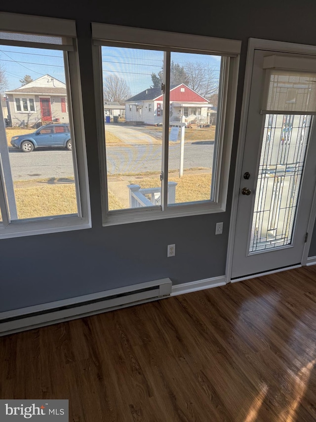 interior space with a baseboard radiator, wood finished floors, a residential view, and baseboards