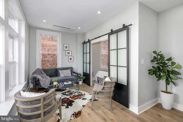 living area with light wood-style floors, a barn door, baseboards, and recessed lighting