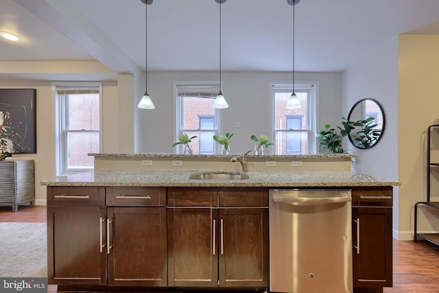 kitchen with dishwasher, wood finished floors, light stone countertops, pendant lighting, and a sink