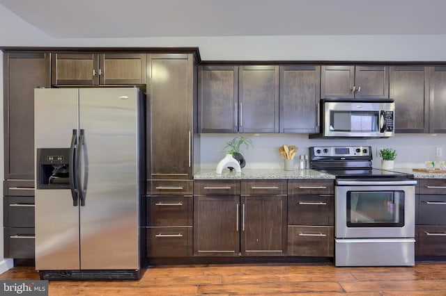 kitchen featuring dark wood-type flooring, appliances with stainless steel finishes, dark brown cabinets, and light stone counters