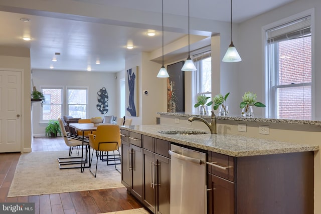 kitchen featuring dark brown cabinetry, hanging light fixtures, stainless steel dishwasher, and wood finished floors