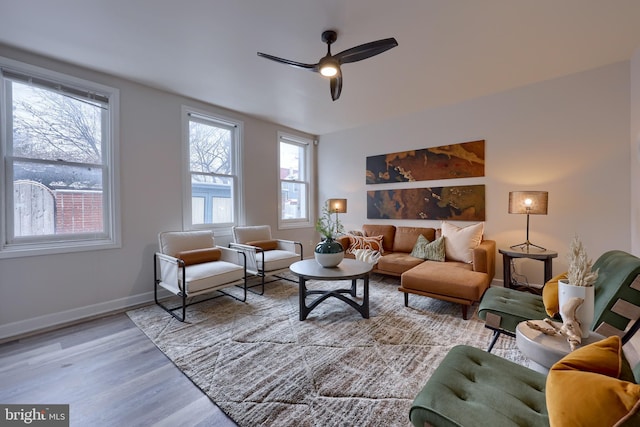 living room featuring light wood-type flooring, a ceiling fan, and baseboards