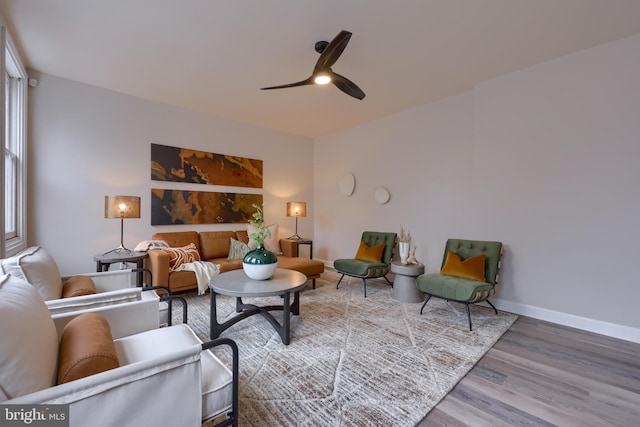 living area featuring a ceiling fan, plenty of natural light, baseboards, and wood finished floors