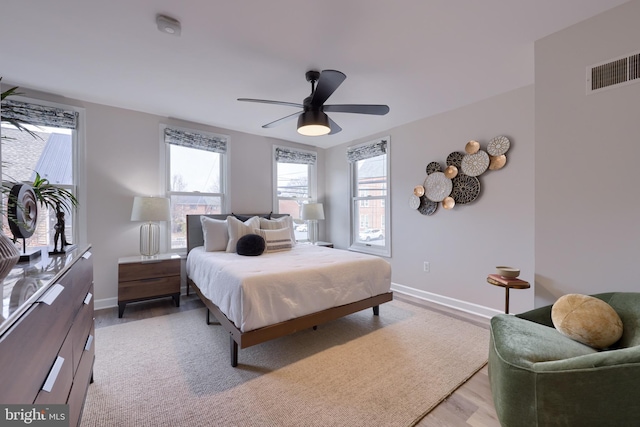 bedroom featuring visible vents, ceiling fan, light wood-style flooring, and baseboards