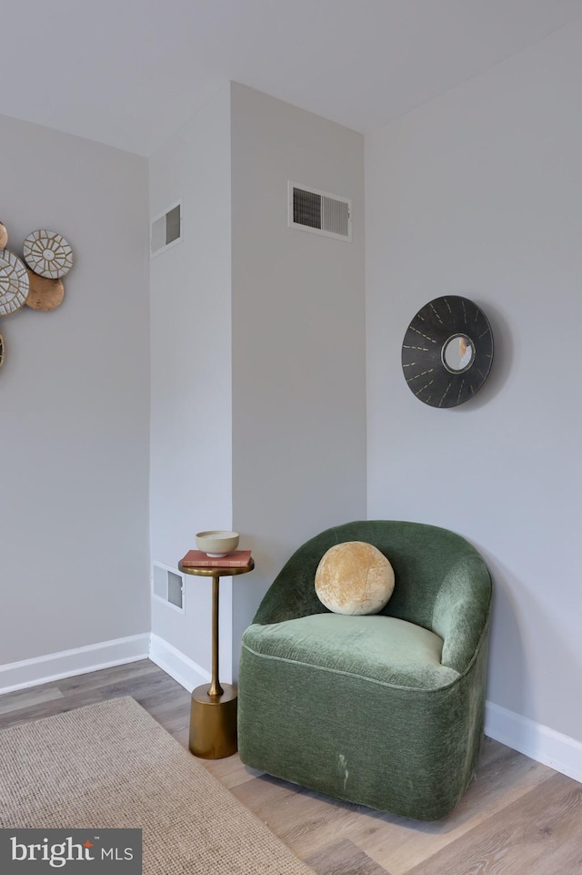 living area featuring baseboards, visible vents, and wood finished floors