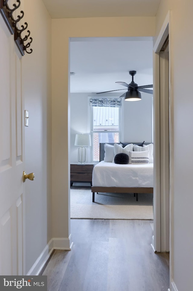 corridor with baseboards and wood finished floors