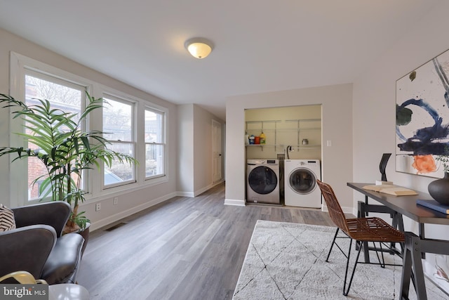 laundry area with laundry area, separate washer and dryer, visible vents, baseboards, and light wood-type flooring