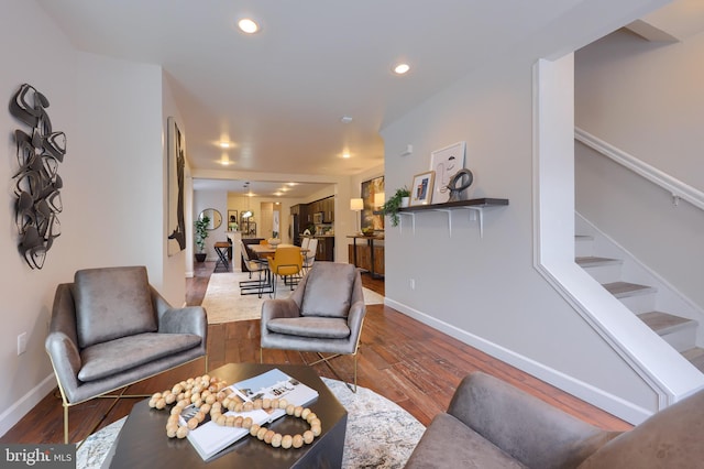 living room featuring baseboards, stairway, wood finished floors, and recessed lighting