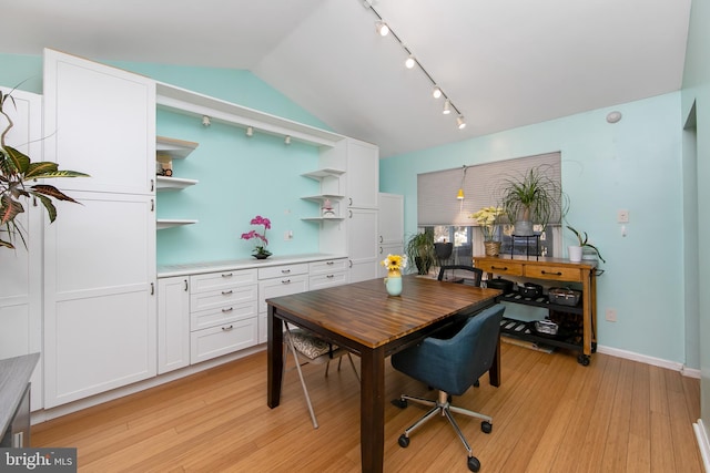 dining space with lofted ceiling, rail lighting, baseboards, and light wood finished floors