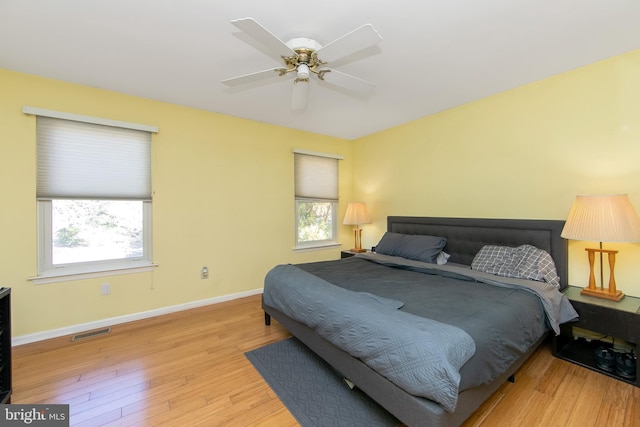 bedroom with baseboards, visible vents, multiple windows, and wood finished floors