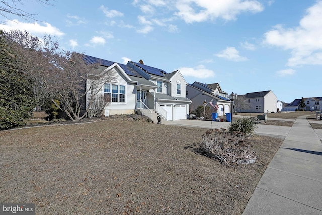 view of front of house with a garage, solar panels, a residential view, and concrete driveway