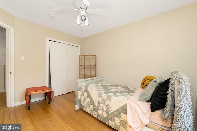 bedroom featuring ceiling fan, a closet, baseboards, and wood finished floors