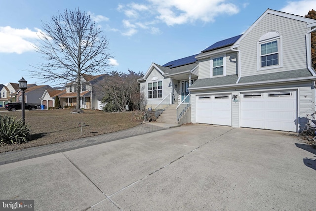 view of front of property featuring a shingled roof, solar panels, concrete driveway, a residential view, and an attached garage