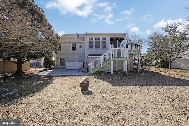 rear view of property featuring a sunroom, stairs, fence, a wooden deck, and a patio area