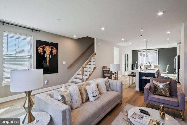 living room with stairway, recessed lighting, light wood-style flooring, and baseboards