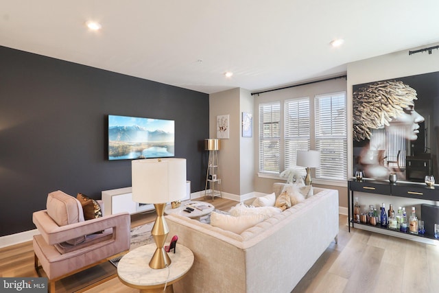 living area with an accent wall, baseboards, wood finished floors, and recessed lighting