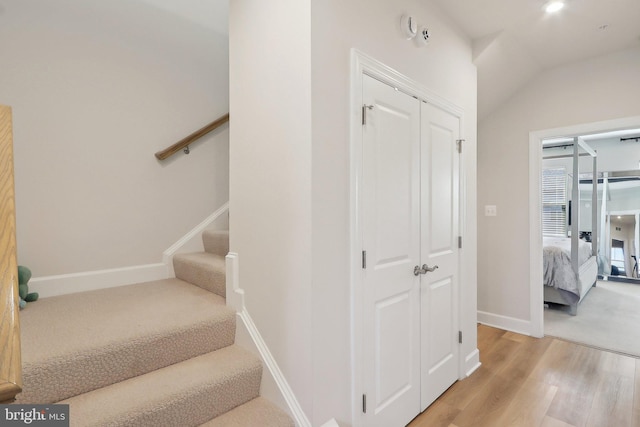 stairs with baseboards, vaulted ceiling, and wood finished floors