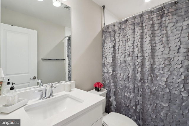 bathroom featuring toilet, a shower with curtain, visible vents, and vanity