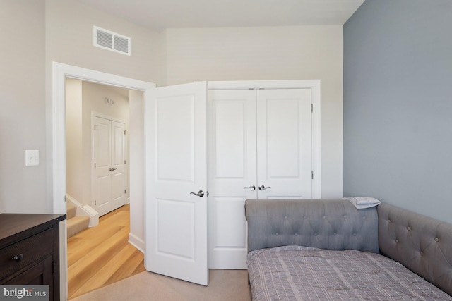 bedroom with light wood-style flooring, visible vents, and a closet