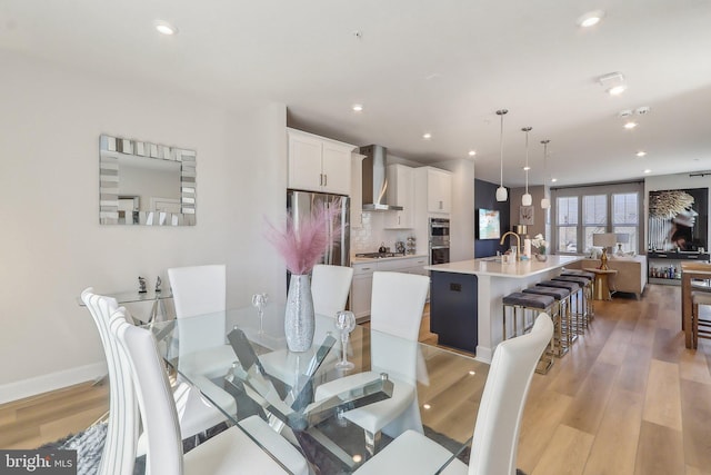 dining space with baseboards, light wood finished floors, and recessed lighting