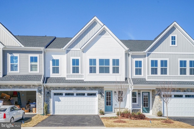 townhome / multi-family property featuring roof with shingles, board and batten siding, and stone siding