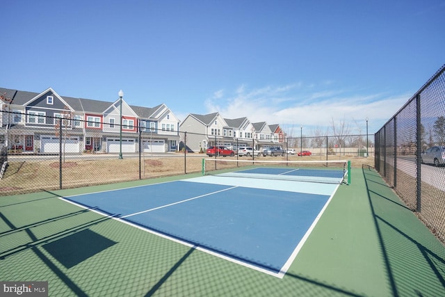 view of tennis court with a residential view and fence