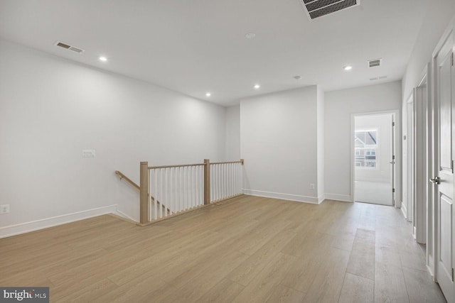 empty room with light wood-style flooring, visible vents, baseboards, and recessed lighting