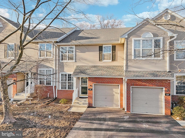 townhome / multi-family property featuring a garage, aphalt driveway, a shingled roof, and brick siding