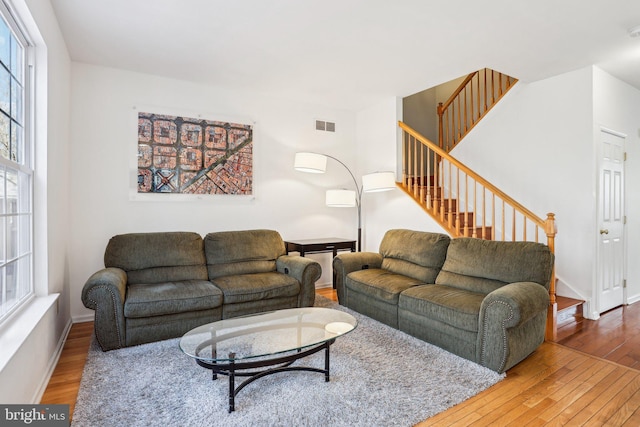 living area featuring a wealth of natural light, stairway, wood-type flooring, and visible vents