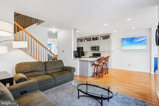 living area featuring light wood-style floors, stairs, and recessed lighting