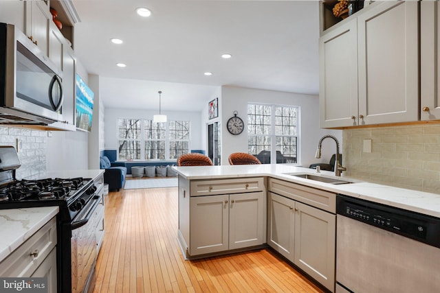 kitchen featuring stainless steel appliances, a wealth of natural light, a sink, and a peninsula