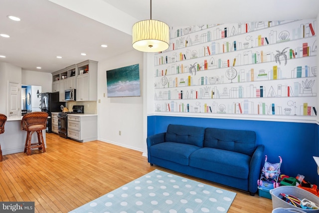 living area featuring light wood-style flooring, baseboards, and recessed lighting