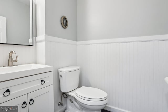 half bath featuring wainscoting, vanity, and toilet