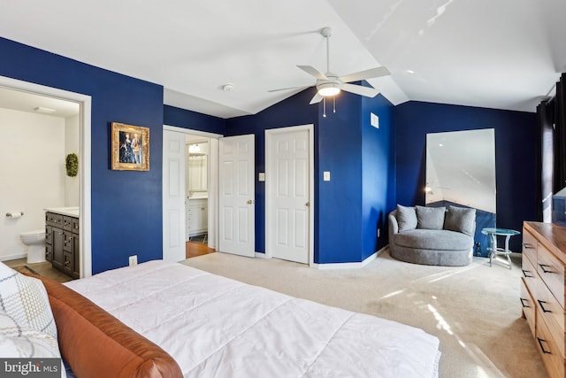 carpeted bedroom featuring vaulted ceiling, ensuite bath, and baseboards