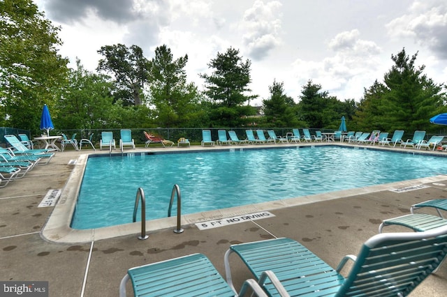 community pool with a patio and fence