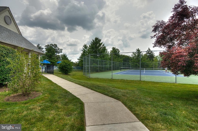 view of sport court featuring a tennis court, a yard, and fence