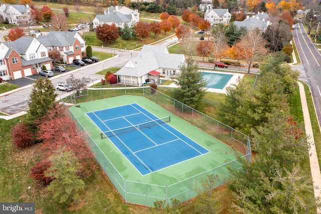 view of tennis court with a residential view and fence