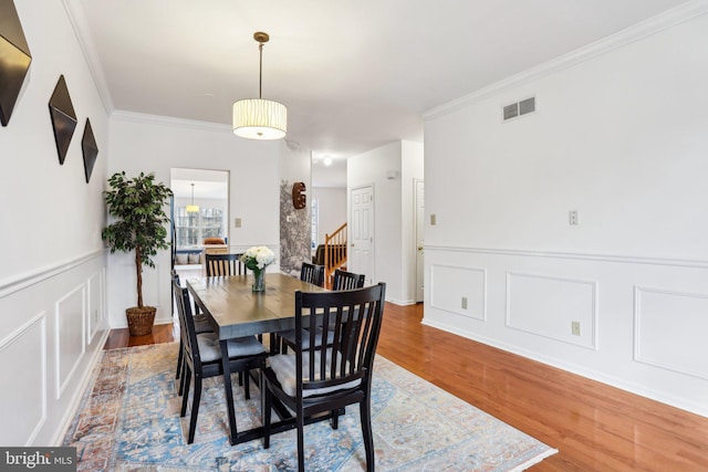 dining area with crown molding, visible vents, and wood finished floors