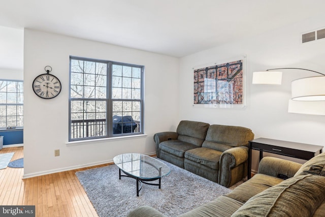 living room featuring wood-type flooring, visible vents, and baseboards