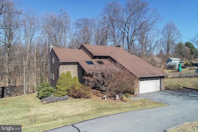 view of side of home featuring a yard, a shingled roof, a chimney, a garage, and brick siding