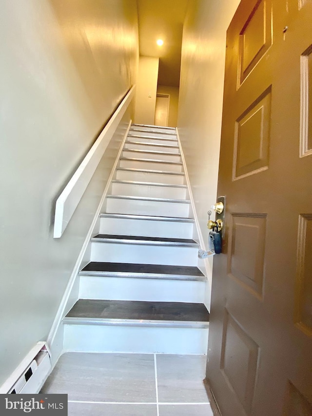 stairs featuring a baseboard heating unit