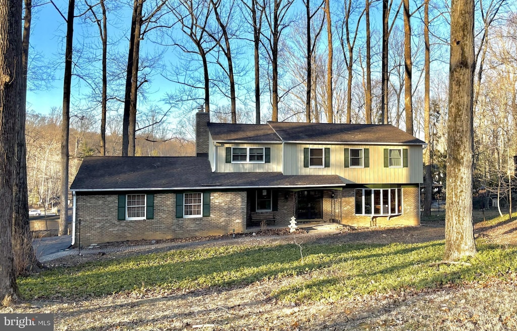 view of front of home with brick siding, a chimney, and a front lawn