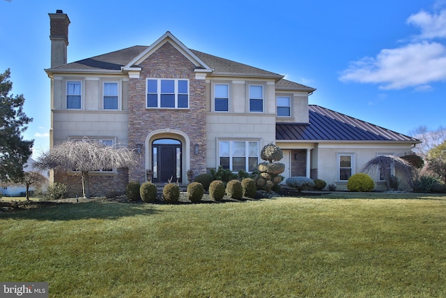 view of front of property with a standing seam roof, a chimney, metal roof, and a front yard