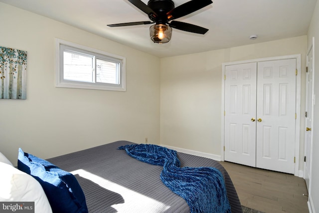 bedroom featuring dark wood-style flooring, a closet, a ceiling fan, and baseboards