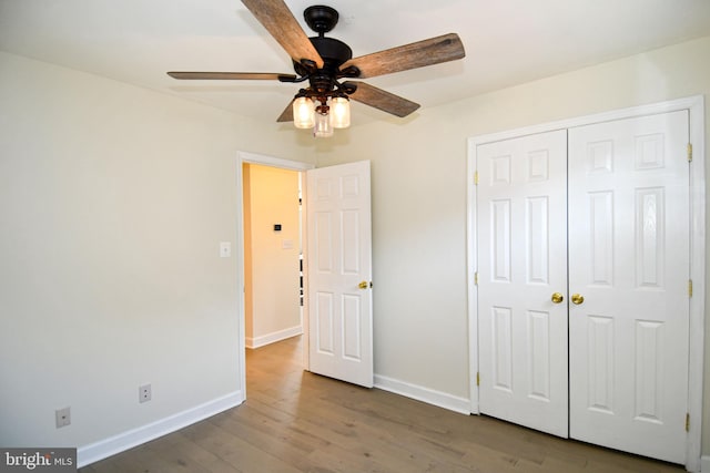 unfurnished bedroom with a closet, dark wood-style flooring, baseboards, and a ceiling fan