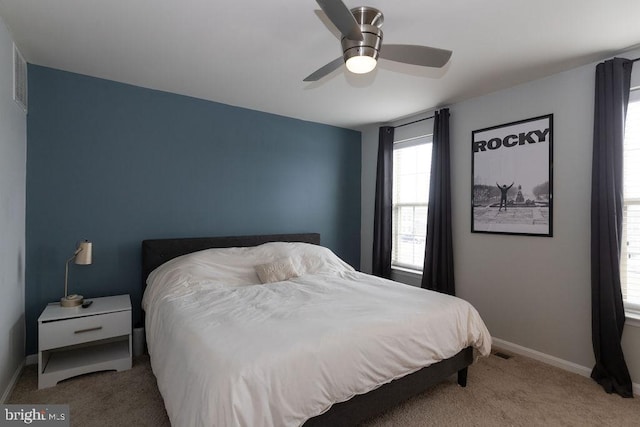 bedroom with a ceiling fan, light colored carpet, visible vents, and baseboards