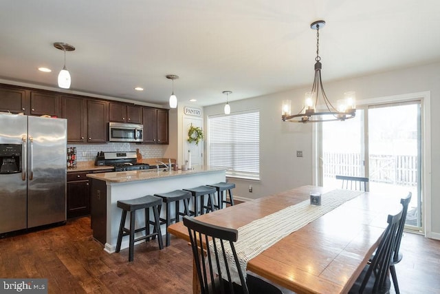 dining space featuring baseboards, a chandelier, dark wood finished floors, and recessed lighting