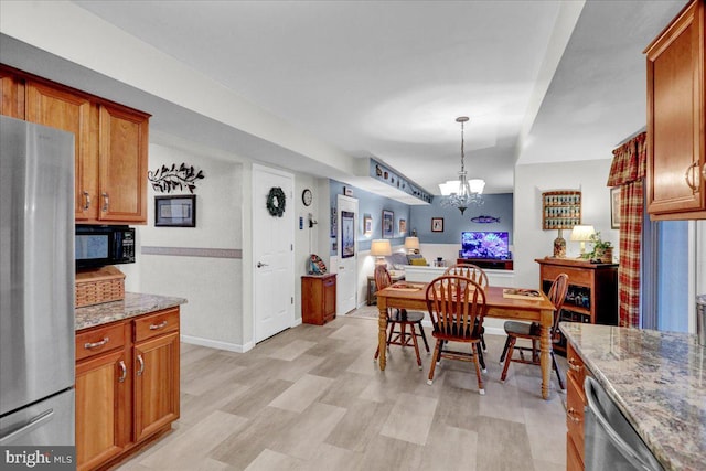 dining room with a chandelier, light wood-style flooring, and baseboards