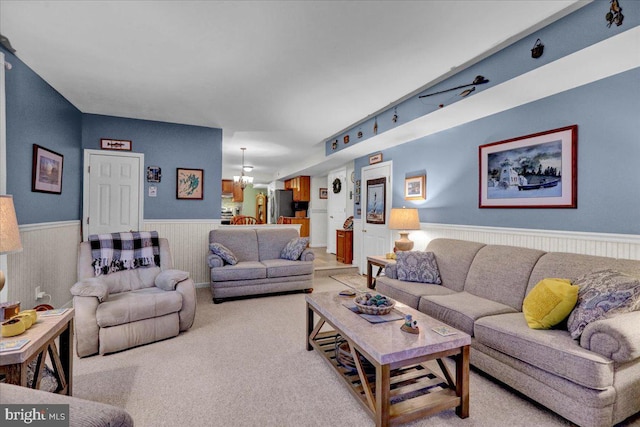 carpeted living area featuring wainscoting and a notable chandelier