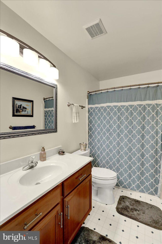 bathroom with toilet, vanity, and visible vents